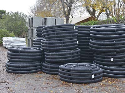 TX Mulching and Dozer Images - Black drainage pipes in coiled bundles and culverts stacked behind